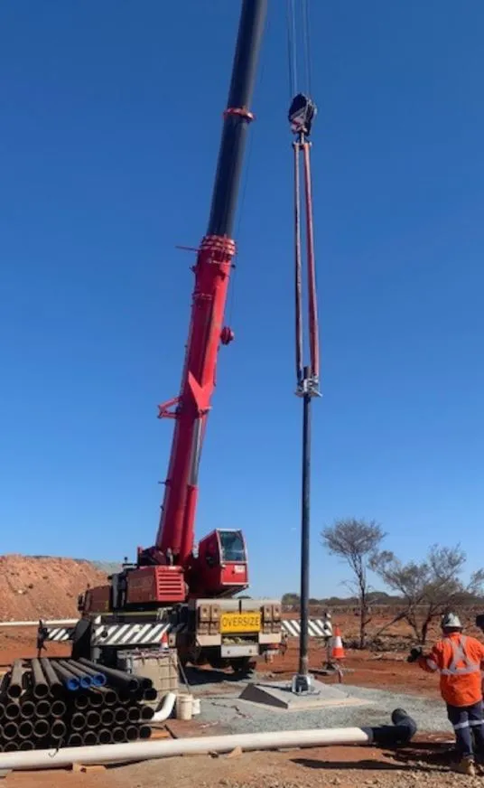 Mobile crane lifting a vertical pump column into place at an outback water pump station