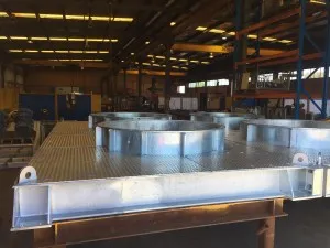 Fabricated steel ventilation fan support structure with circular fan housings in a workshop
