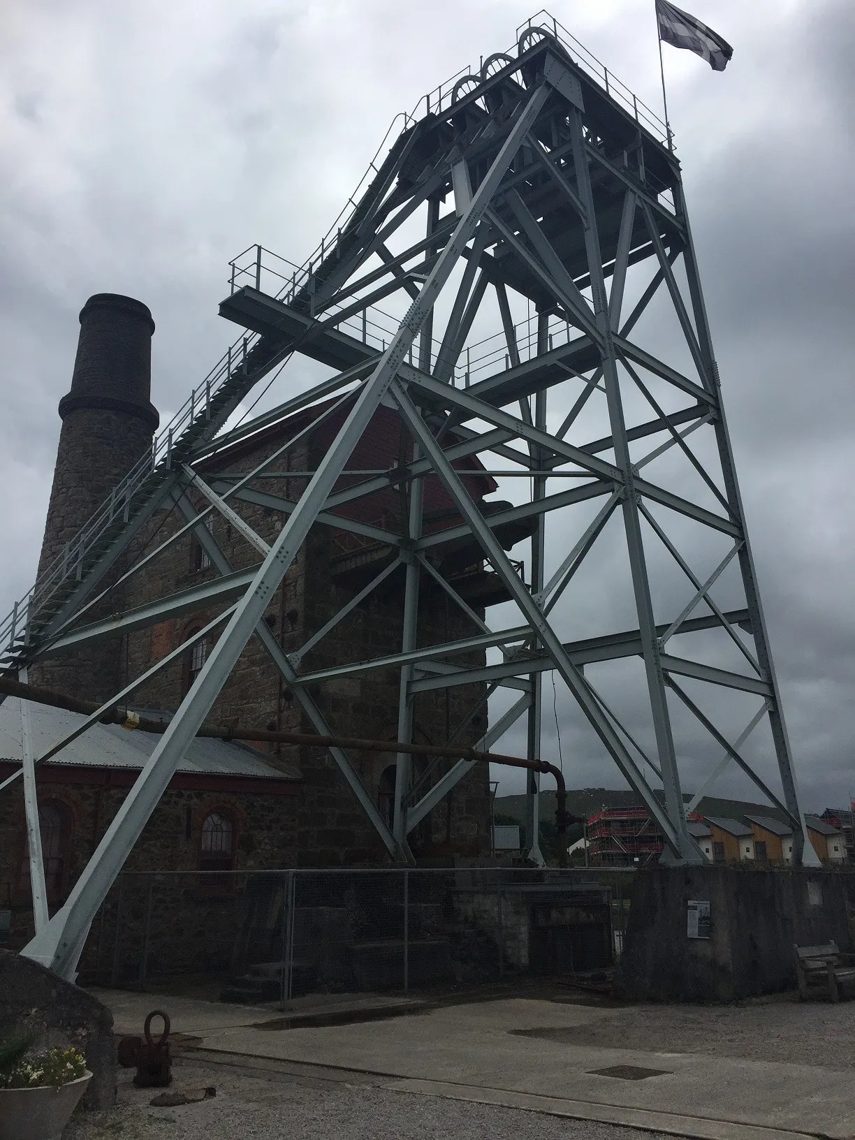 Steel headframe and stone engine house with chimney at a former Cornish tin mine