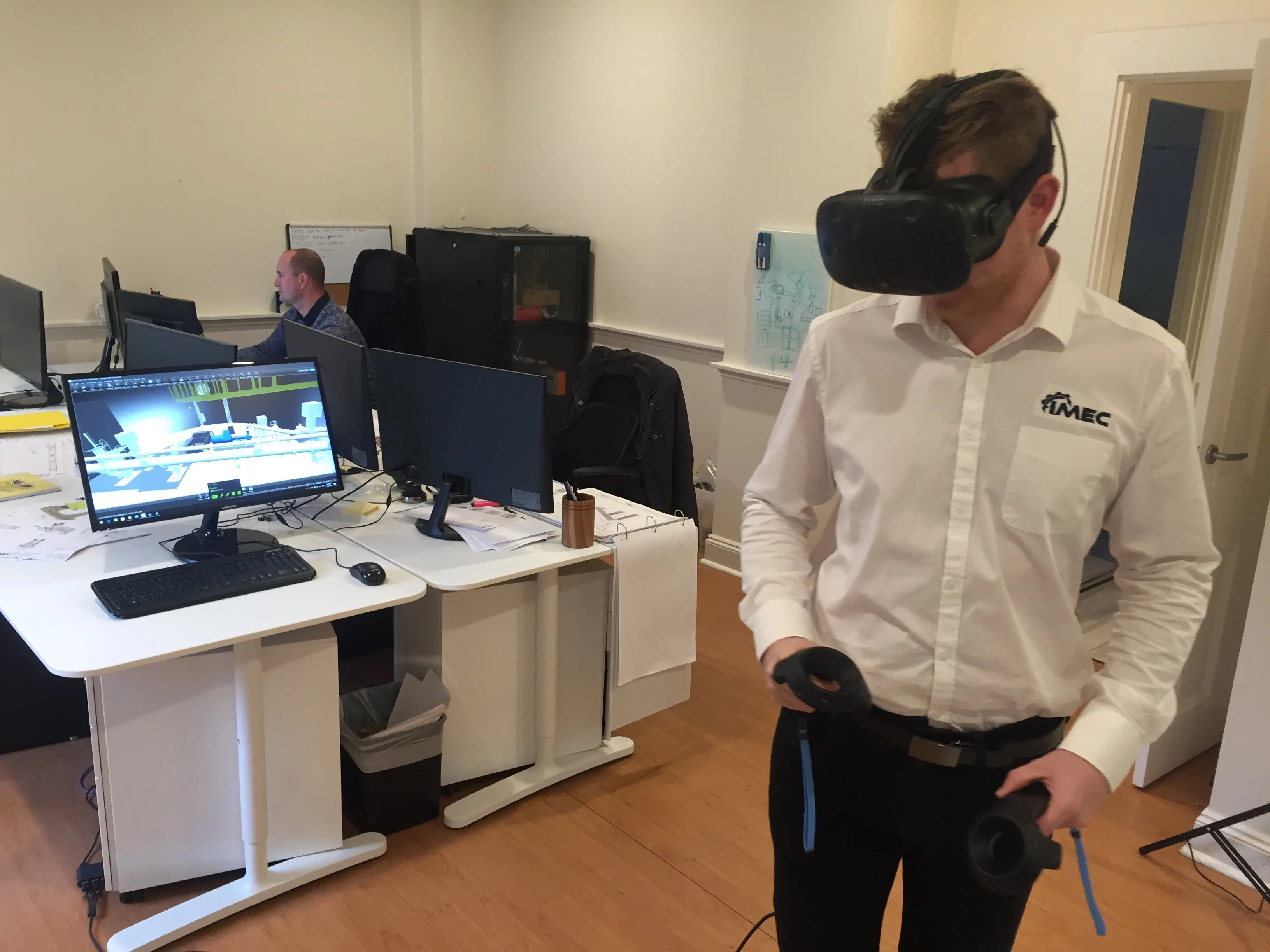 IMEC engineer wearing a VR headset and controllers reviews a 3D pump station model in the office