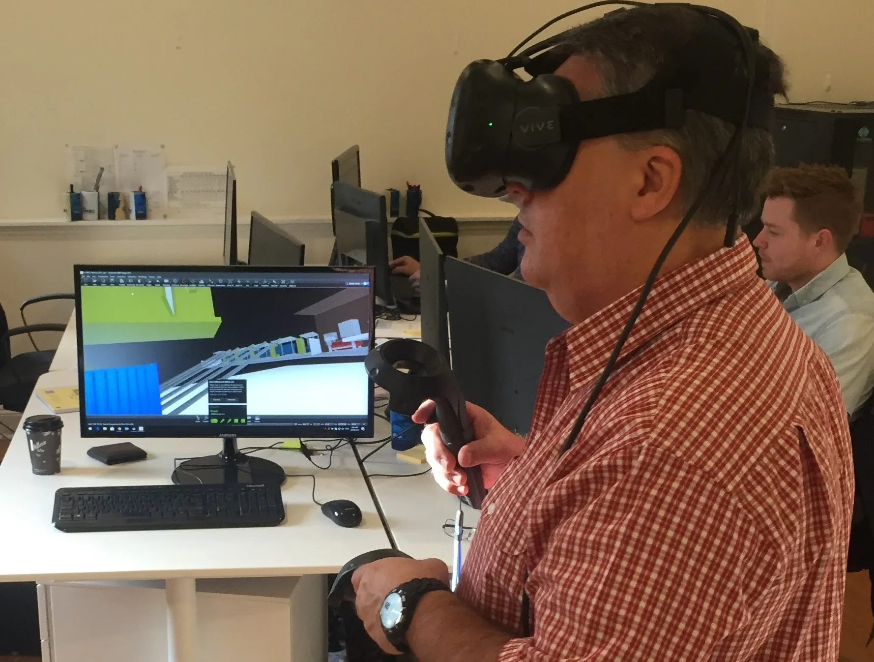 Engineer wearing a VR headset and holding a controller while reviewing a 3D mine pump station model on screen