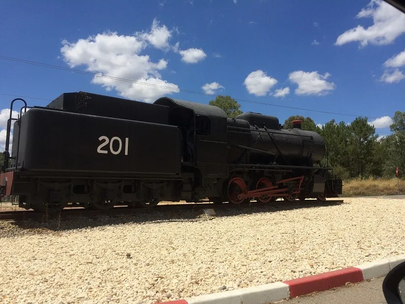 Preserved black steam locomotive numbered 201 on display track beside a gravel yard
