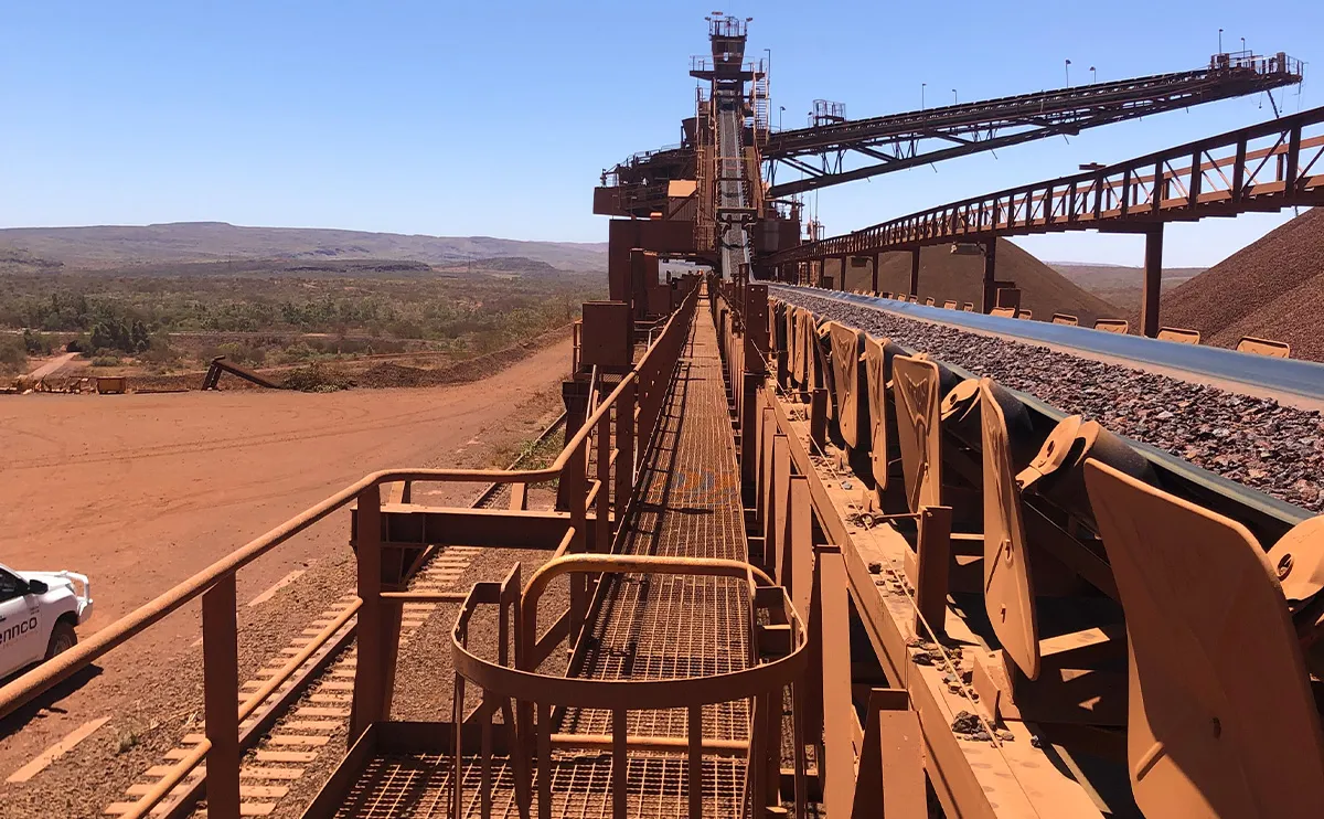Overhead conveyor and stacker structure carrying iron ore across a Pilbara mine site walkway
